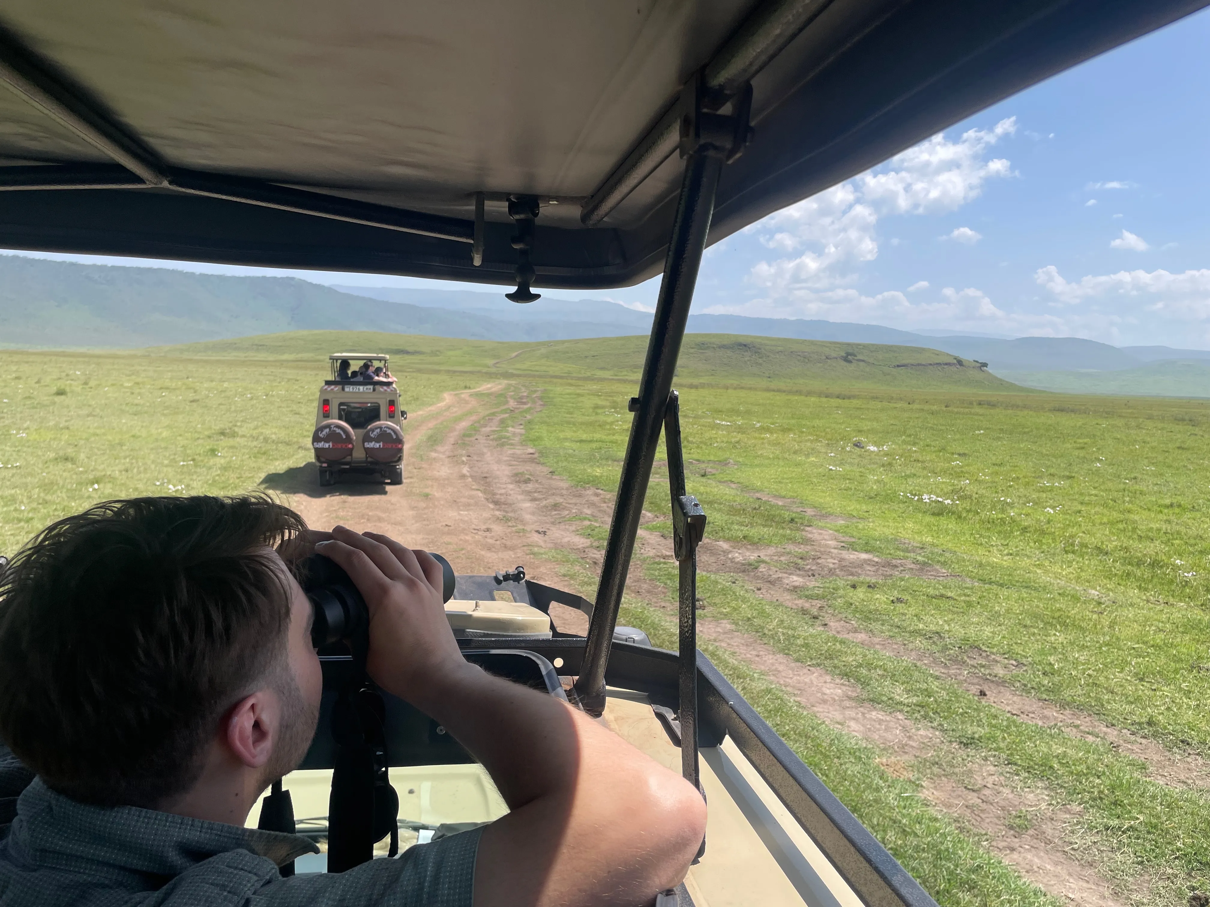 Watching wildlife through binoculars from a safari vehicle in Ngorongoro Crater